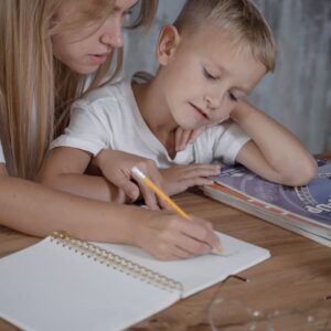 A Boy Looking at the Handwritten of the W0oman Sitting Beside Him